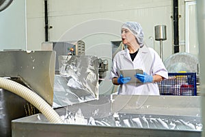 caucasion woman working in a food factory wearing protective clothes and gloves