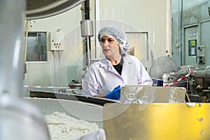 caucasion woman working in a food factory wearing protective clothes and gloves