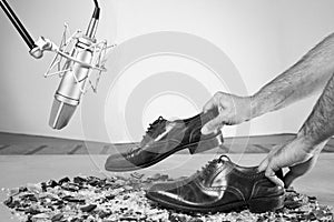 Caucassian male hands with male dress shoes moving on broken glass and near to a studio mic on Black & white version