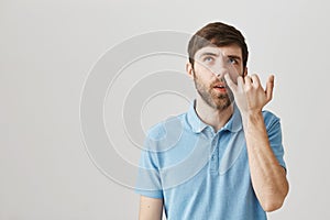 Caught on doing bad things. Indoor shot of spaced out unworried mature man looking up with dumb expression while picking photo