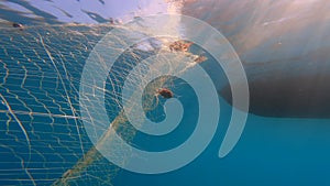 Caught Fish in Net Hanging From Boat Under Sea