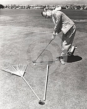 Caught between a rake and a gardening fork on the putting green