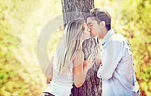 Caught up in the romance. Shot of a young couple kissing by a tree.