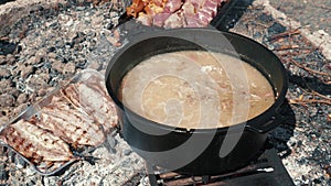 Cauldron with kulish prepared on fire. Picnic time. Barbecue meat frying on fire