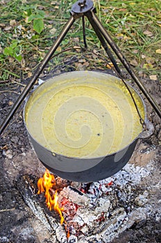 A cauldron in which kulesh is boiled hangs on a tripod over the fire