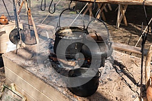 Cauldrons hang on hooks over the fire