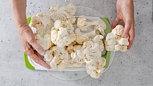 Cauliflower close-up on cutting board on kitchen table, woman hands