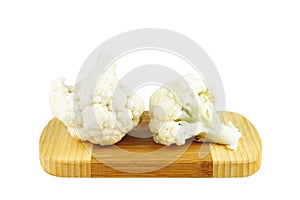 Cauliflower pieces on wooden cutting board isolated on white