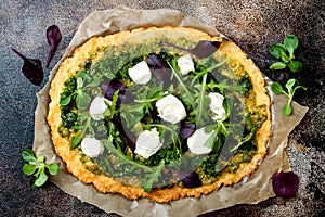 Cauliflower pizza crust with pesto, kale, mozzarella cheese and greens.