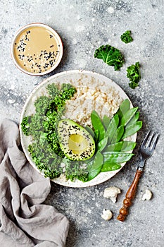 Cauliflower rice Buddha bowl with kale, avocado, seeds, snow peas and tahini dressing.