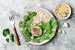 Cauliflower rice Buddha bowl with kale, avocado, seeds, snow peas and tahini dressing. photo