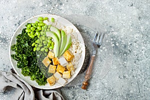 Cauliflower rice Buddha bowl with massaged kale, tofu, avocado and edamame beans. Vegan poke bowl.