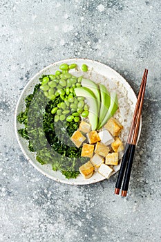 Cauliflower rice Buddha bowl with massaged kale, tofu, avocado and edamame beans. Vegan poke bowl.