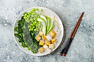 Cauliflower rice Buddha bowl with massaged kale, tofu, avocado and edamame beans. Vegan poke bowl.