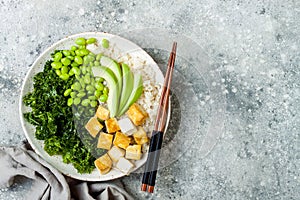 Cauliflower rice Buddha bowl with massaged kale, tofu, avocado and edamame beans. Vegan poke bowl.