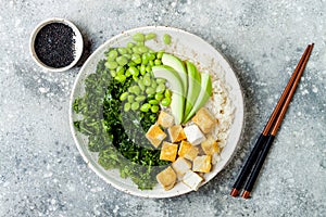 Cauliflower rice Buddha bowl with massaged kale, tofu, avocado and edamame beans. Vegan poke bowl. photo