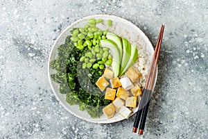 Cauliflower rice Buddha bowl with massaged kale, tofu, avocado and edamame beans. Vegan poke bowl. photo