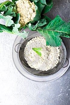 Cauliflower rice in metal bowl on grey background. Top view. Overhead. Copy space. Shredded