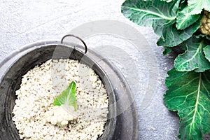 Cauliflower rice in metal bowl on grey background. Top view. Overhead. Copy space. Shredded