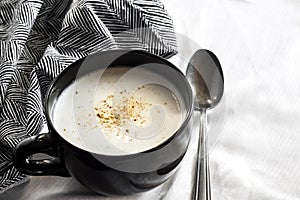 Cauliflower Soup Creme du Barry in black bowl on white background with black and white cloth