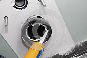 Caulking a closet flange, toilet flange of a wall mounted toilet. Toilet flange installation by glueing it to the wall with a