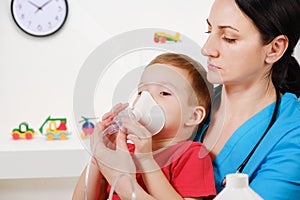 Causian little boy making inhalation with nebulizer at hospital.