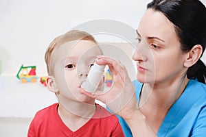 Causian little boy making inhalation with nebulizer at hospital.