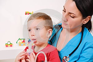 Causian little boy making inhalation with nebulizer at hospital