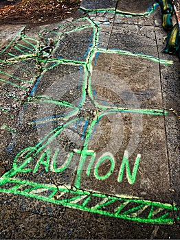 Caution Chalk Sign on Broken Pavement