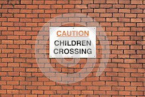 Caution children crossing road safety sign on school wall