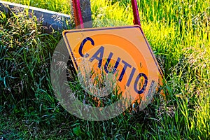 A caution construction sign laying in the grass