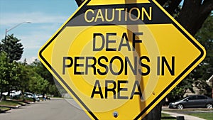 Caution deaf persons in area diamond sign in black writing on yellow background