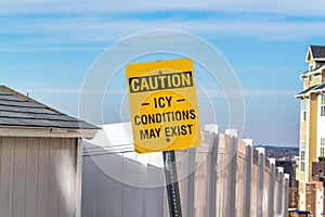 Caution Icy conditions May Exist signage on a sunny neighborhood in winter