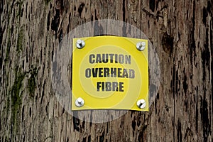 Caution Overhead Fibre Warning Sign on a Wooden Electricity Pole