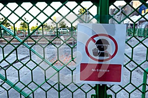 Caution sign on fence of construction site with prohibition sign and text to no entrance
