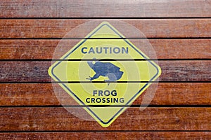 Caution sign, frogs crossing, painted on a wooden bridge