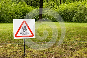 `Caution squirrels` sign is installed on the grass in the park