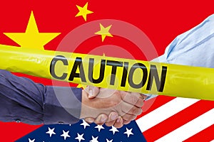 Caution tape over businessmen handshaking on Usa or American and China flags merged politic and economic relationships concept