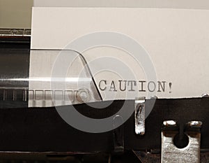 Caution text typed on old black typwriter
