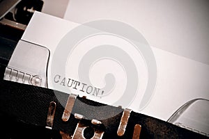 Caution text typed on old black typwriter