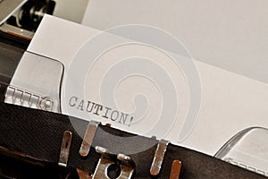 Caution text typed on old black typwriter
