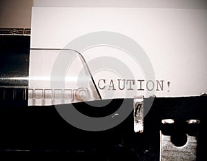 Caution text typed on old black typwriter