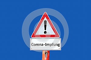 Caution warning sign corona vaccination on blue background in german photo