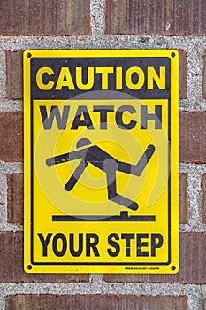 Caution Watch Your Step sign on a brick wall