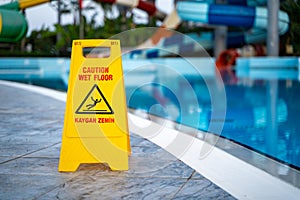 Caution wet floor warning sign near swimming pool in hotel