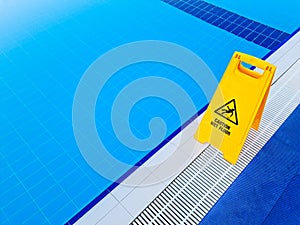 Caution Wet Floor. Yellow sign near the pool