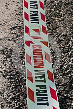 Caution wet paint on a plastic tape on tarmac