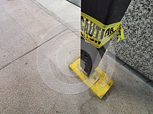 Caution yellow tape wrapped around metal frame construction pole of steel scarffolding during renovation