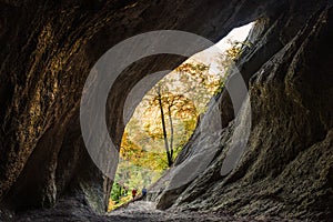 Cave in autumn nature, two Cavers walking out from the cave