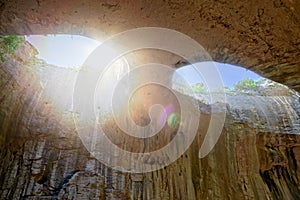 Cave ceiling with holes in the form of eyes from which the sun is shining